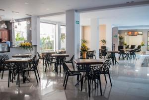 a dining room with tables and chairs and windows at Hotel Pairumani in Cochabamba