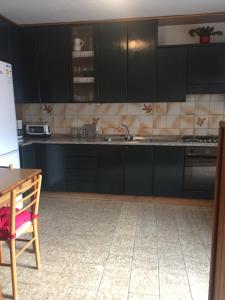 a kitchen with black cabinets and a sink and a table at Casa Montana 1600 in Sovramonte +17 photos