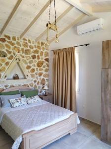 1 dormitorio con cama y pared de piedra en Oliveways, en Liapades