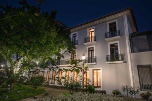 biały budynek z oknami i balkonami w nocy w obiekcie Azoris Angra Garden – Plaza Hotel w mieście Angra do Heroísmo