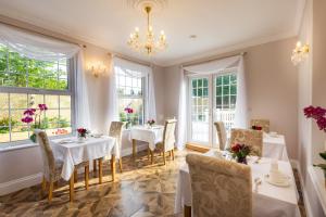a dining room with tables and chairs and windows at Rockleigh Place in St Austell