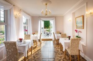 a dining room with white tables and chairs and a chandelier at Rockleigh Place in St Austell