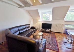 a living room with a leather couch and a flat screen tv at duplex apartment - city centre - airconditioned - netflix - 2 balconies in Heidelberg