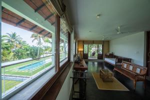 a living room with a large window and a pool at amã Stays & Trails, Pathiramanal Villa in Alleppey