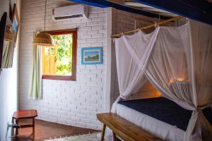 a bedroom with a canopy bed and a window at Pousada Le Refuge in Trancoso