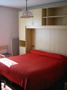 a bedroom with a bed with a red blanket at Hotel Cime d'Auta in Falcade