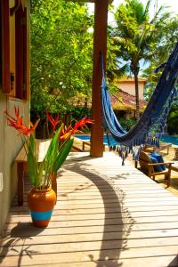 a porch with a hammock and flowers in a vase at Pousada Le Refuge in Trancoso