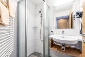 a bathroom with a shower, sink, and toilet at Hotel Garni Siegmundshof in Saalbach-Hinterglemm