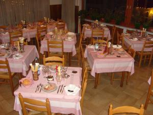 un comedor con mesas blancas y sillas con platos de comida en Hotel Cime d'Auta, en Falcade