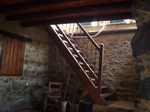 a wooden staircase in a room with a stone wall at Patriko Traditional House in Kakopetria