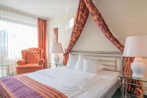 a bedroom with a large bed and a chair at Romantik Parkhotel am Hammerberg in Stolberg
