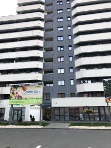 un gran edificio de apartamentos con un cartel delante en Alpha Apartment en Brasov