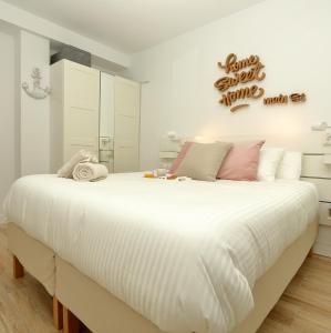 ein Schlafzimmer mit einem großen Bett mit weißen Laken und rosa Kissen in der Unterkunft Home Sweet Home Main St Pamplona in Pamplona