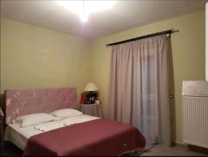 1 dormitorio con 1 cama con cabecero rosa en Athinas House en Katastárion