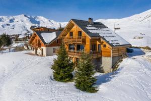 a wooden house in the snow with mountains in the background at Chalet l'Alpette in La Toussuire