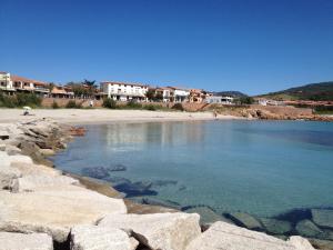 a beach with rocks and houses in the background at Dimore Dell'Isola Rossa in Isola Rossa