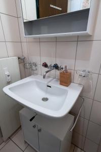 W łazience znajduje się biała umywalka i lustro. w obiekcie Panorama at Haus Waldheim Nr. 11 w mieście Grächen