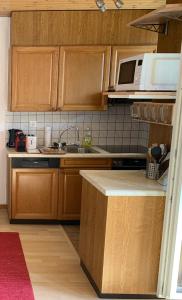 eine Küche mit Holzschränken, einer Spüle und einer Mikrowelle in der Unterkunft Panorama at Haus Waldheim Nr. 11 in Grächen