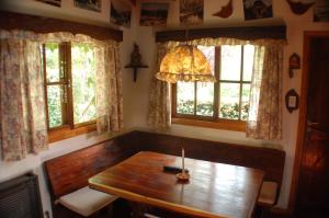 a dining room with a wooden table and two windows at Cabañas Am Hang in La Cumbrecita