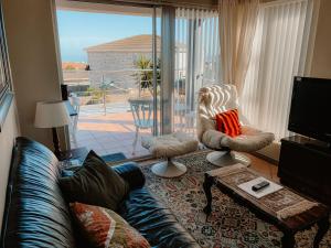 a living room with a couch and chairs and a large window at Sunbird View in Langebaan