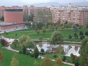 a park with a pond and trees and buildings at Gestión de Alojamientos Rooms in Pamplona