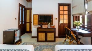 a living room with a desk and a television at The Mansion Hoi An by Minova in Hoi An