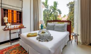 a bedroom with a large white bed with a window at The Mansion Hoi An by Minova in Hoi An