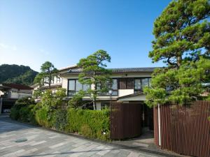 dom z płotem i drzewami przed nim w obiekcie Shinpuro w mieście Miyazu