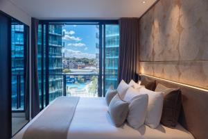 a bedroom with a large bed with a large window at SKYE Suites Green Square in Sydney