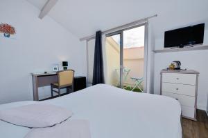 um quarto com uma cama branca, uma secretária e uma janela em Azur Hotel em Balaruc-les-Bains