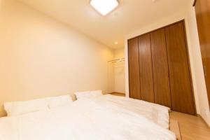 a bedroom with a white bed and a wooden cabinet at Kyoto Backyard Fox in Kyoto