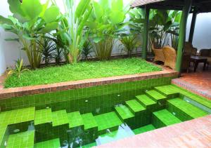 a backyard with a pool with green tiles and plants at Villa Maydou Boutique Hotel in Luang Prabang