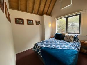 une chambre avec un lit avec une couette bleue et une fenêtre dans l'établissement Ropers, à Dinner Plain