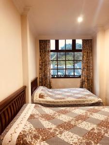 2 łóżka w sypialni z oknem w obiekcie Hotel Chua Gin w mieście Cameron Highlands