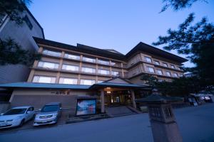 un edificio con dos coches estacionados frente a él en Hotel Miya Rikyu en Miyajima