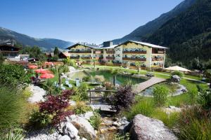a resort in the mountains with a pond and a bridge at Gästehaus Edelweiss in Krimml