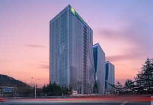 um edifício alto com um sinal verde em Holiday Inn Express Qingdao Innovation Park, an IHG Hotel em Qingdao