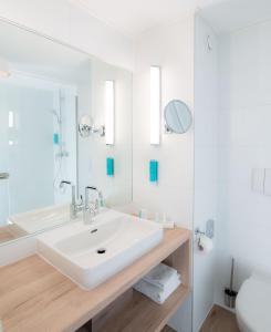 a white bathroom with a sink and a mirror at Hotel Metropol in Sankt Pölten