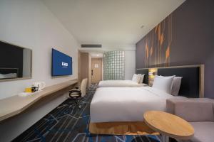 a hotel room with two beds and a tv at Holiday Inn Express Qingdao Innovation Park by IHG in Qingdao