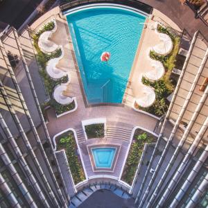 - une vue sur la piscine avec une personne qui s'y baigne dans l'établissement SKYE Suites Green Square, à Sydney