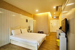 1 dormitorio con 1 cama blanca y TV en Forever Sunny B&B en Ruifang