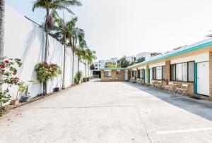 une rue vide avec des palmiers et des bâtiments dans l'établissement Hibiscus Motel, à Byron Bay