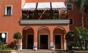 an orange building with a balcony with potted plants at Artemis Hotel in Cefalù