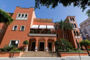 a red brick building with a staircase in front of it at Artemis Hotel in Cefalù