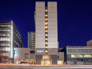 大分ART Hotel Oita的一座高大的白色建筑,晚上有灯