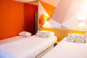 ラ・ロッシュ・シュル・ヨンにあるinitial by balladins La Roche-sur-Yonのオレンジ色の壁の客室内のベッド2台