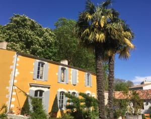 a palm tree in front of a yellow building at Chambres d'hôtes La Borderie du Gô près de La Rochelle - Nieul in Nieul-sur-Mer