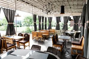 ein Restaurant mit Tischen, Stühlen und Fenstern in der Unterkunft Lviv Ramada Hotel in Lwiw