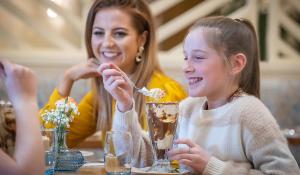 a woman and a girl sitting at a table eating dessert at The Connacht Hotel in Galway