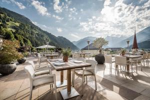 a patio with tables and chairs with mountains in the background at Stock Resort in Finkenberg